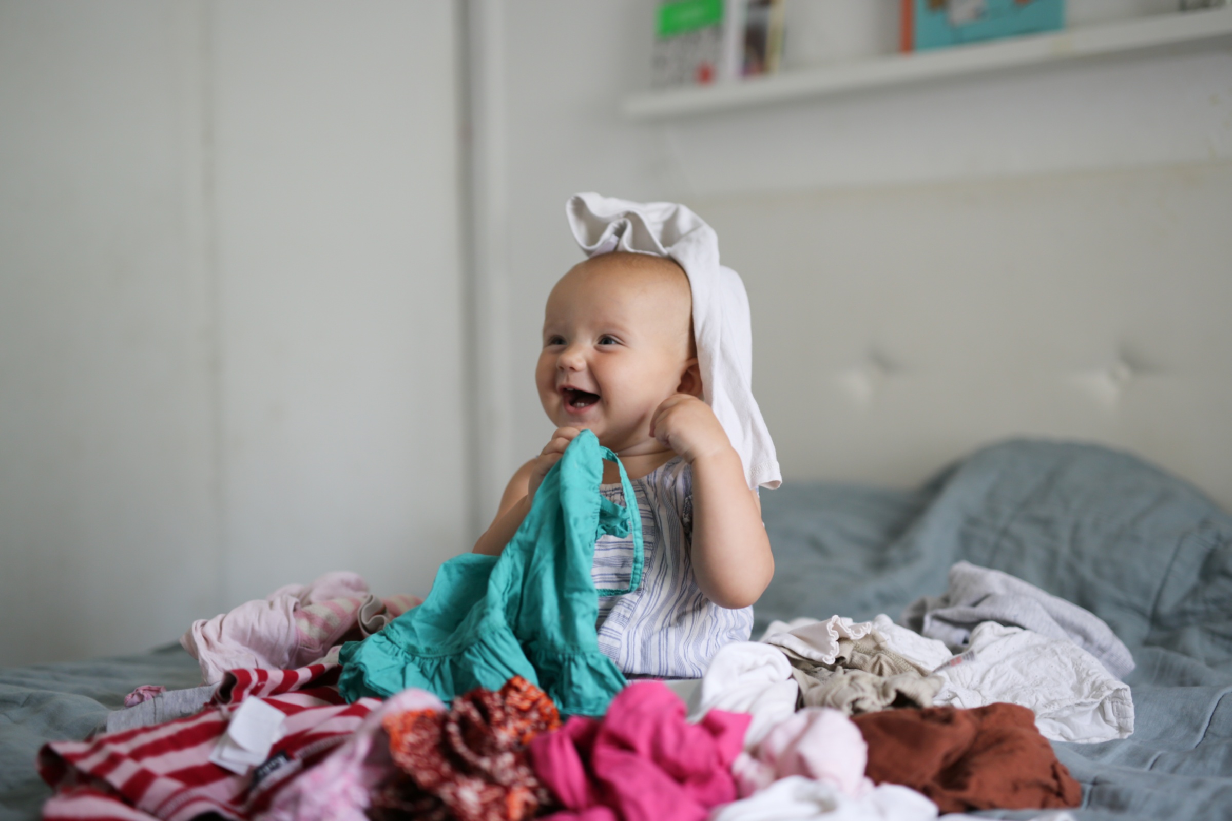 Baby spielt auf Bett mit Kleidung