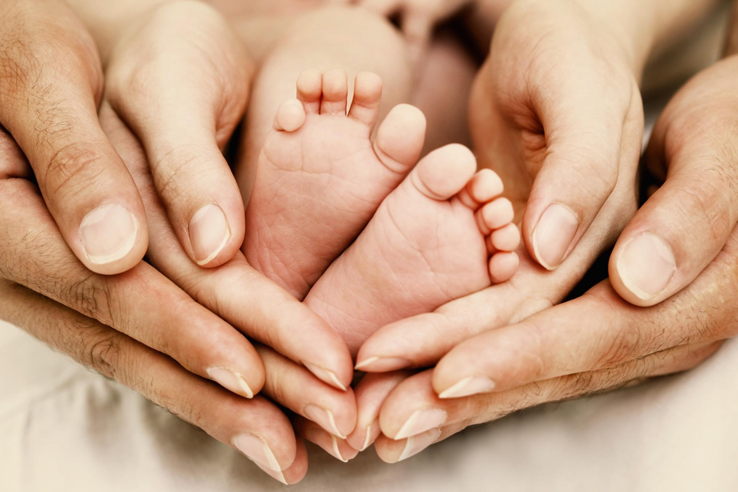 Elternhände umfassen Babyfüße