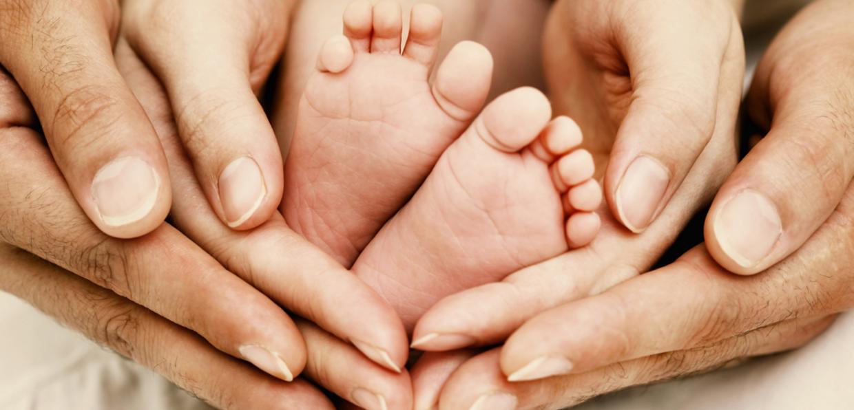 Elternhände umfassen Babyfüße