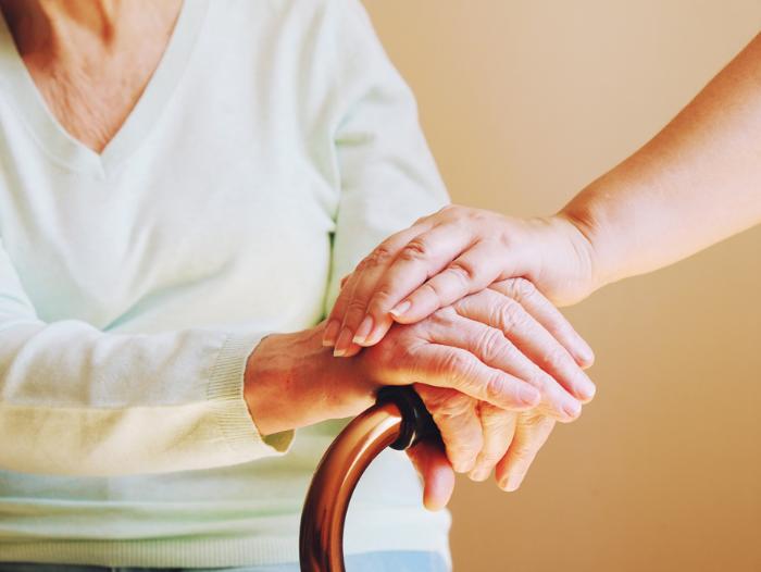 Eine Hand lieg auf denHänden einer Seniorin
