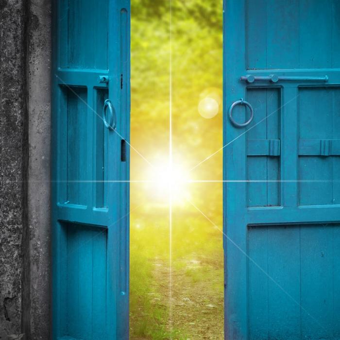 Eine Tür öffnet sich hin auf eine strahlende Sonne.