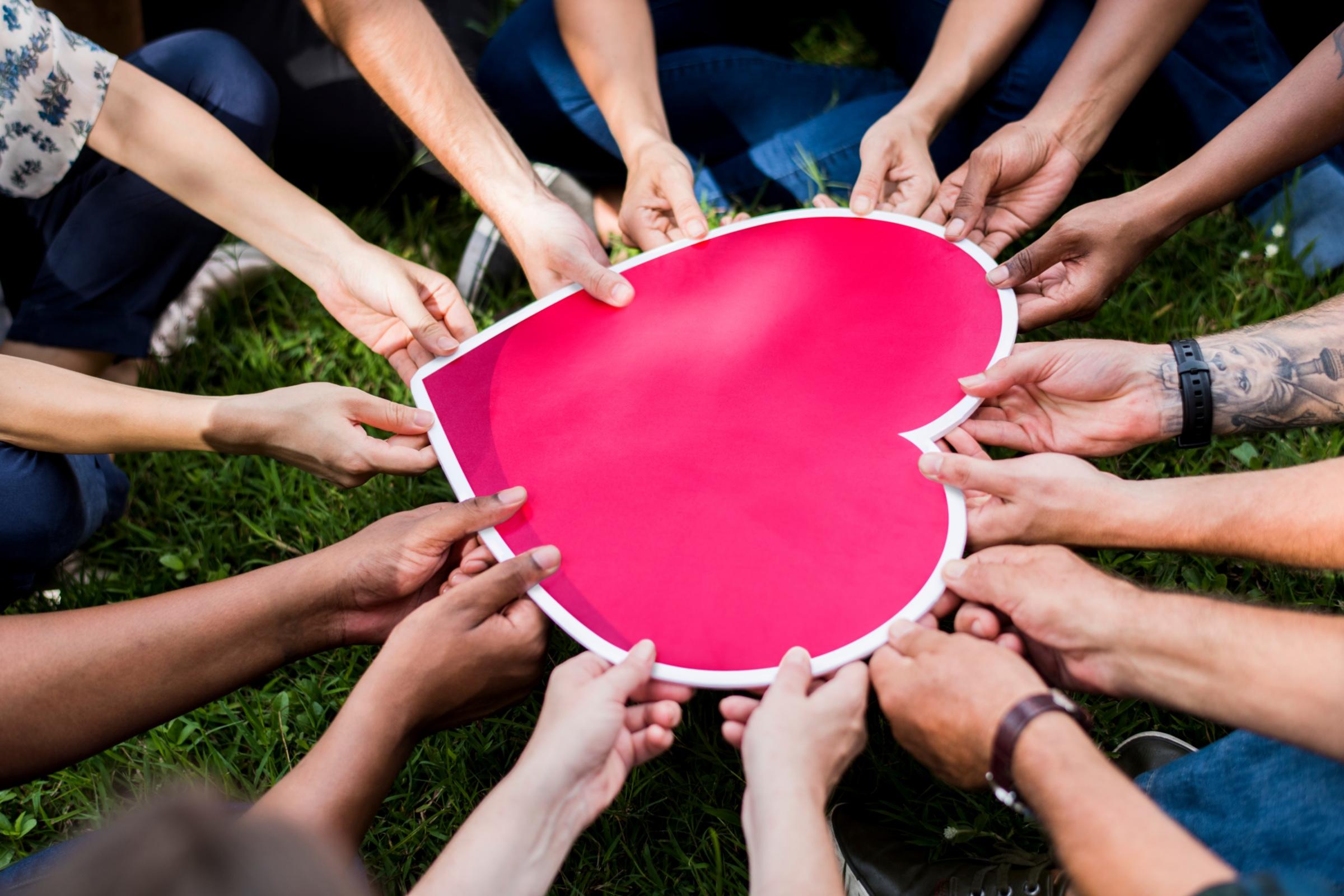 shutterstock_1244940034_Vielfalt_verschiedene_Hände_halten_Herz_rosa_frei