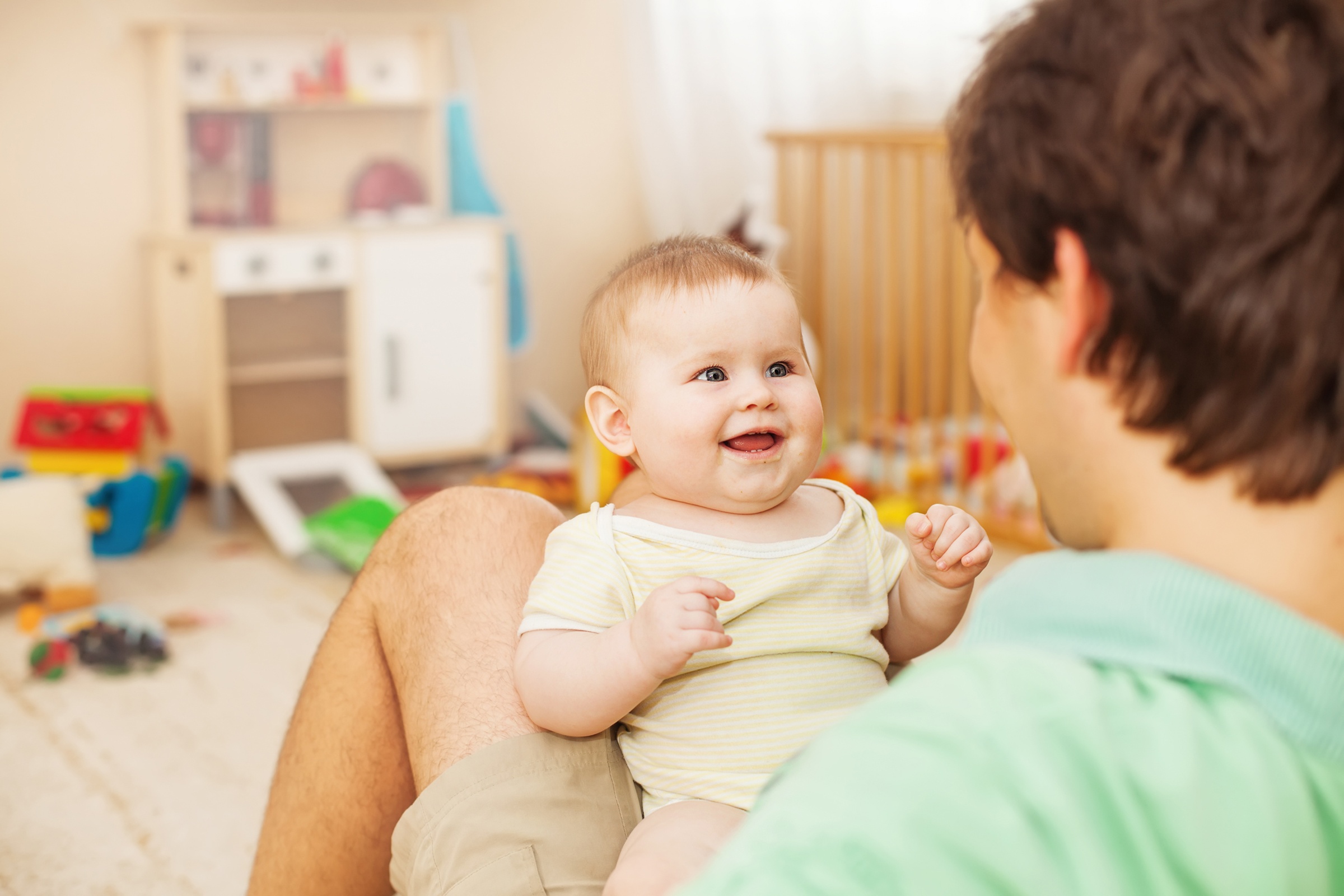 shutterstock_218714161_Kinderzimmer_Vater_hält_Baby_auf_Beinen_frei
