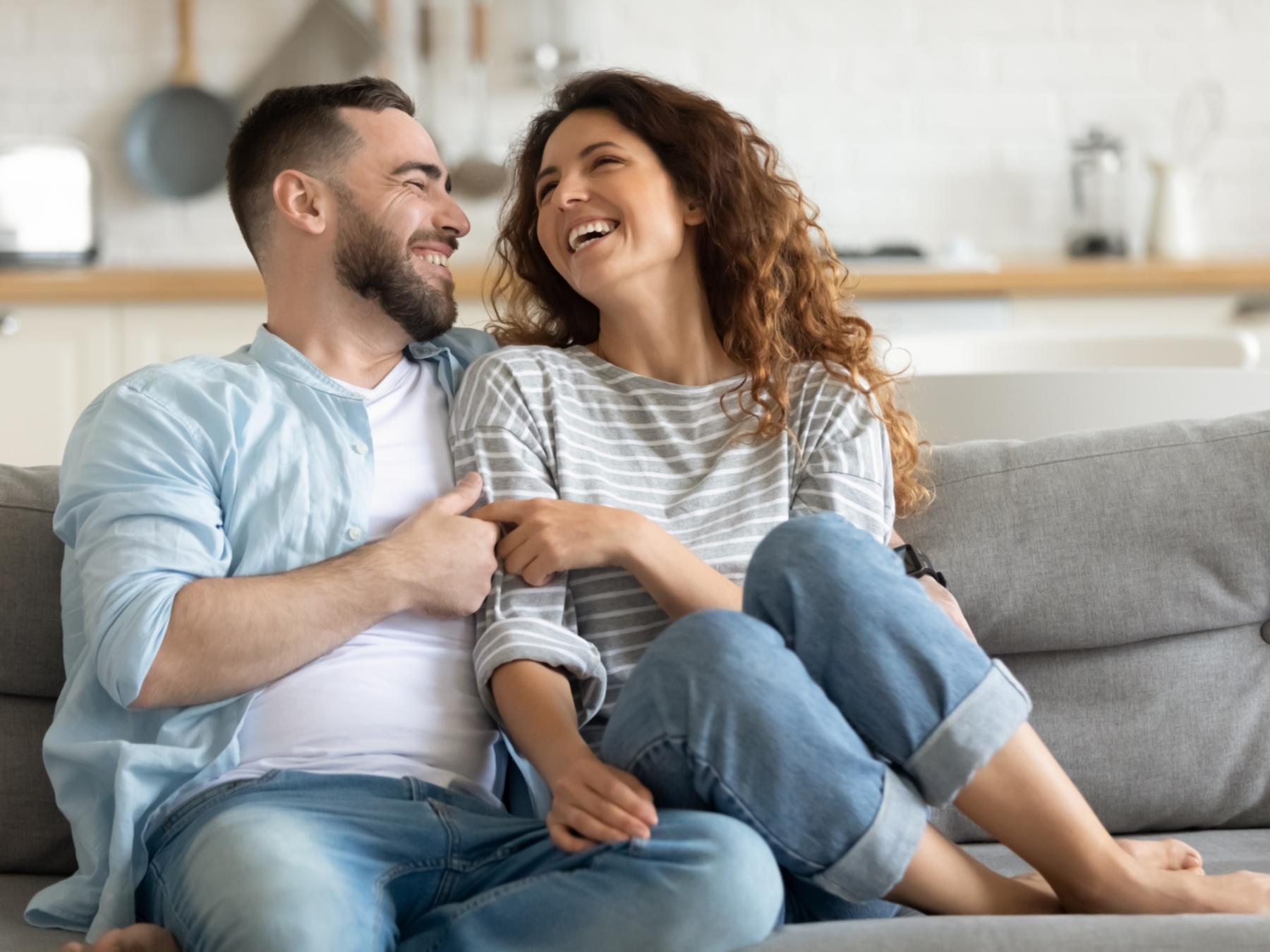 shutterstock_1838823604_junges_Paar_zuhause_lacht_Sofa_frei