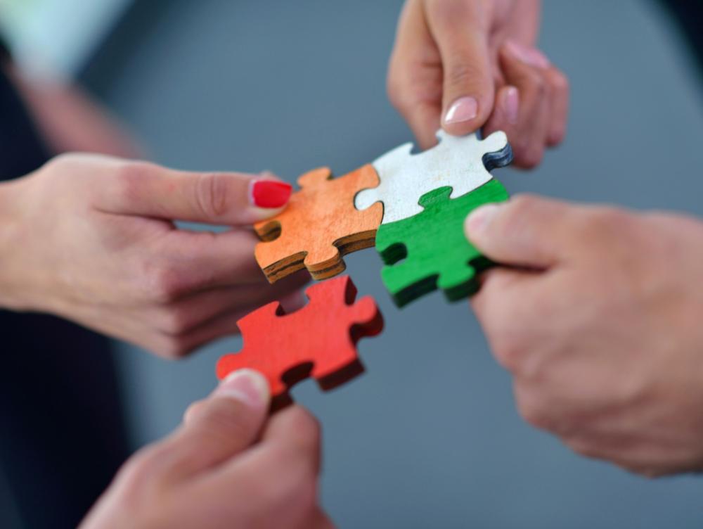 Hände setzen bunte Puzzleteile zusammen.