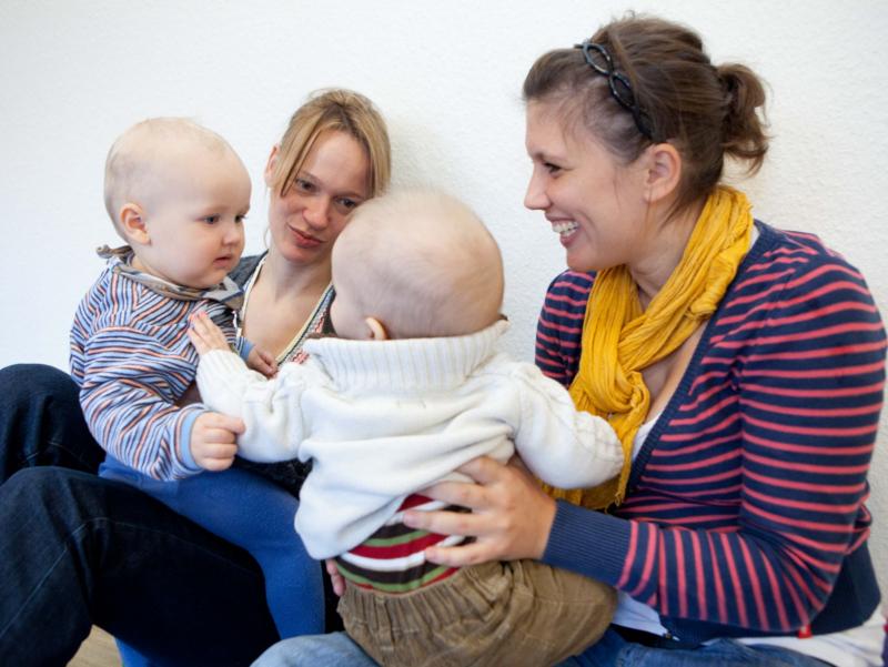 Zwei Mütter mit zwei Kleinkindern auf dem Schoß im Austausch