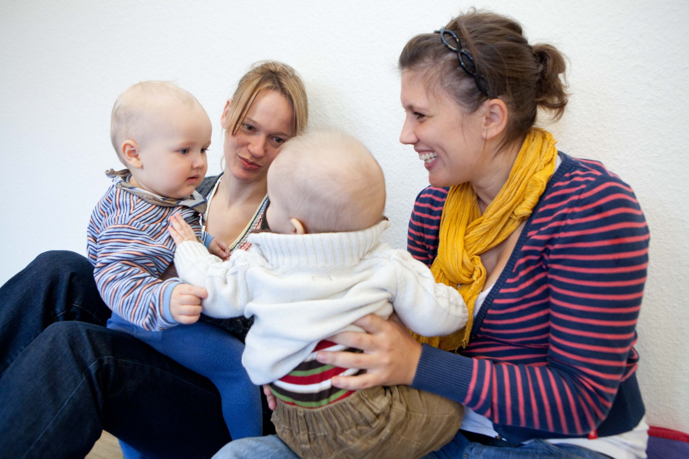 Zwei Mütter mit zwei Kleinkindern auf dem Schoß im Austausch