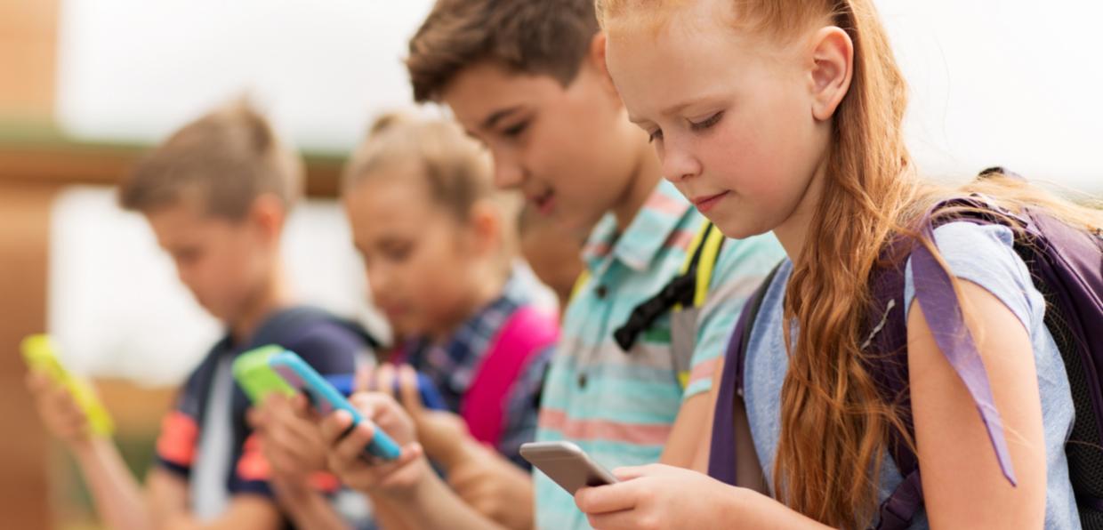 Schulkinder schauen auf das Smartphone
