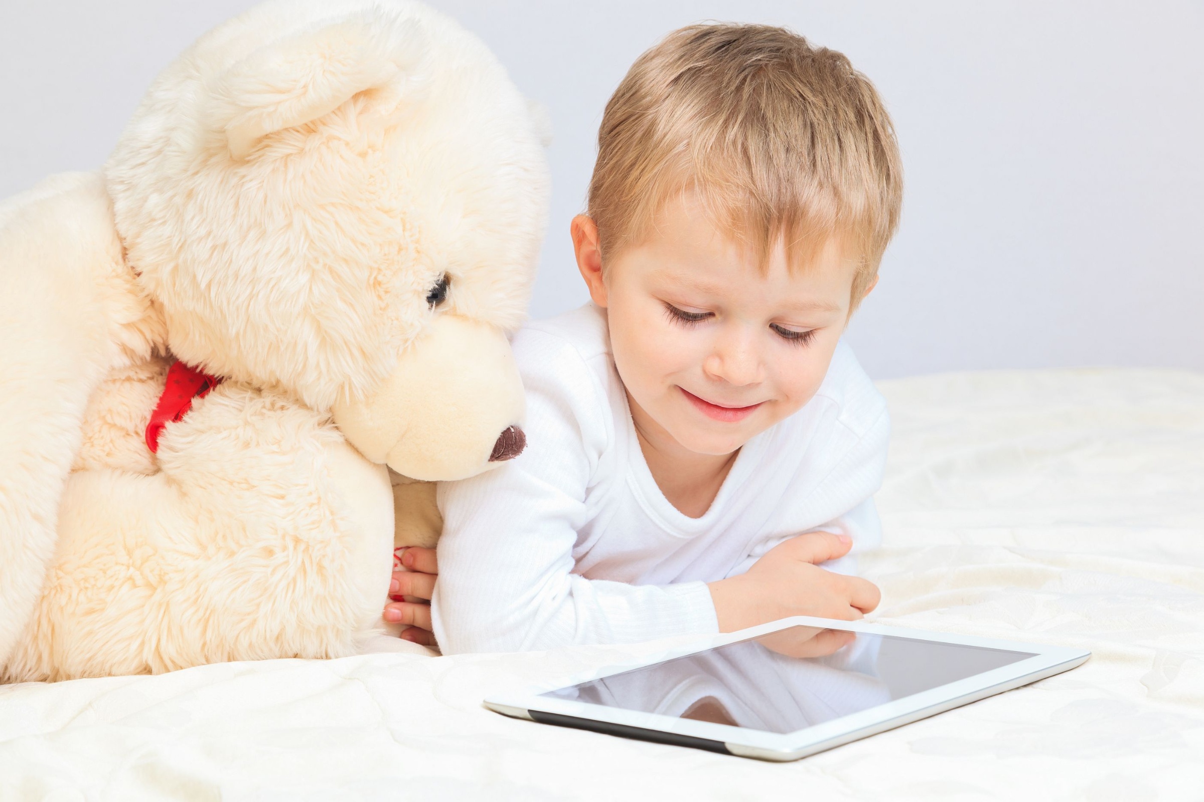 shutterstock_397184551_NadyaEugene_Kind_und_Teddybär_am_Tablet_frei