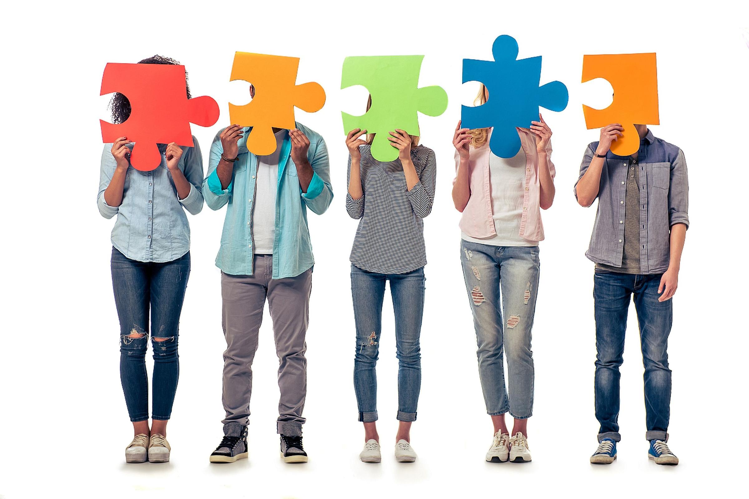 shutterstock_428443576_ GoodStudio_verschiedene_Menschen_halten_bunte_Puzzleteile_vorm_Gesicht_frei